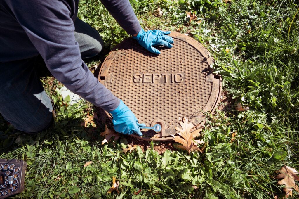 Person inspecting a septic tank cover.